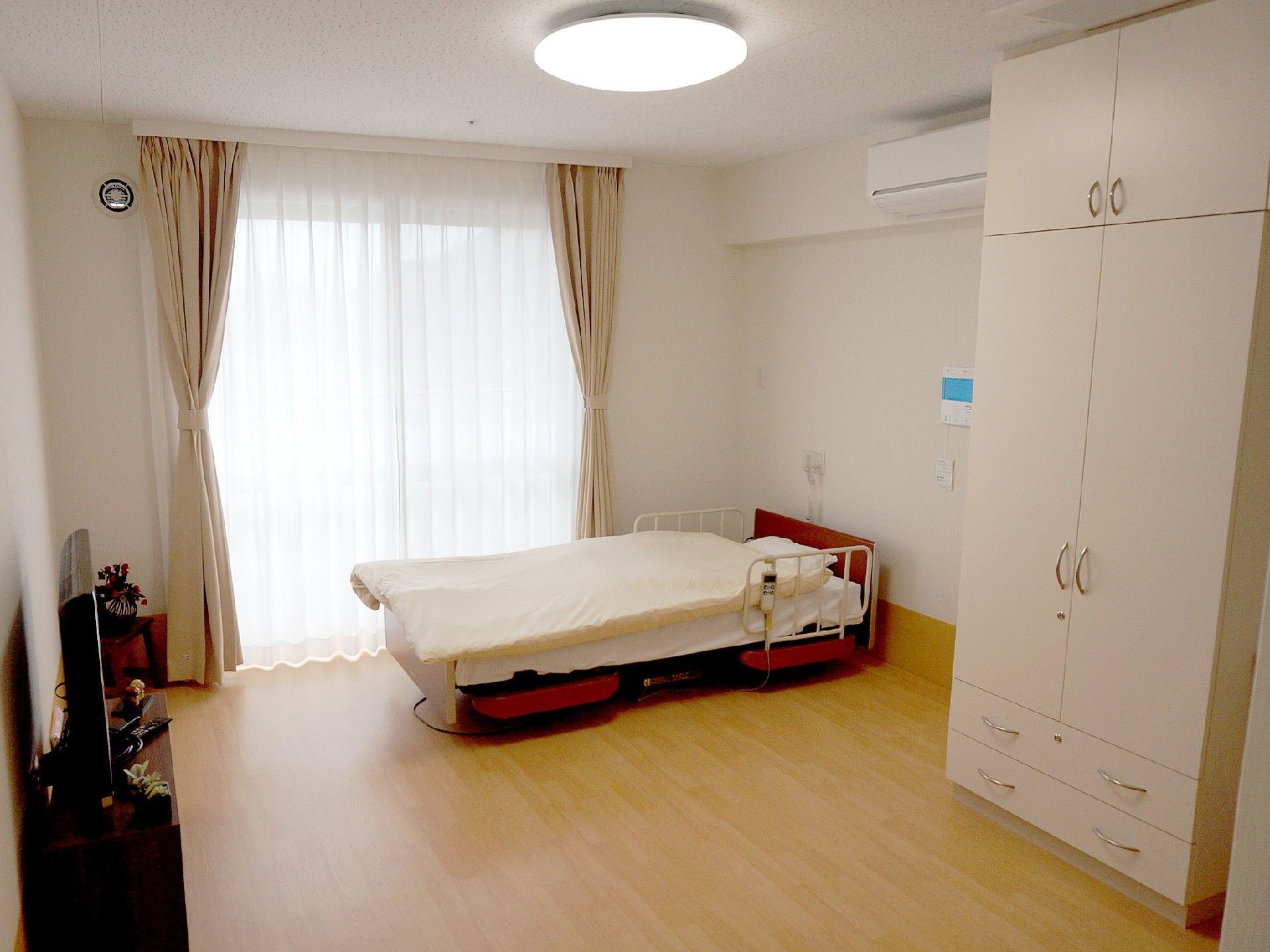 部屋は完全個室で、エアコン、タンス、介護用ベッドが備え付けている。フローリングの床でたっぷりとしたスペースがある。