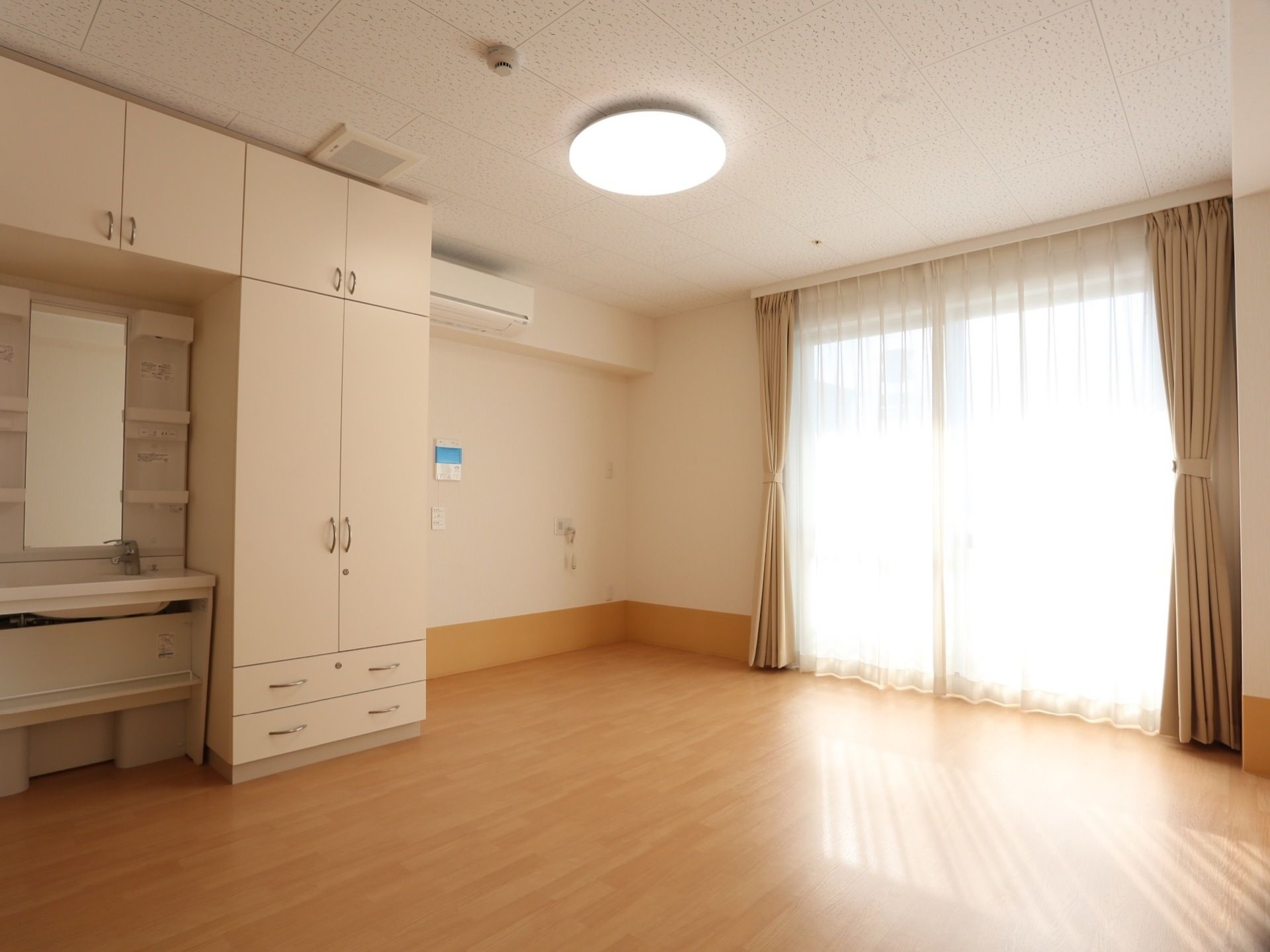 広々とした個室になっている。部屋には洗面台と収納棚が設置されている。エアコンと照明器具が用意されている。