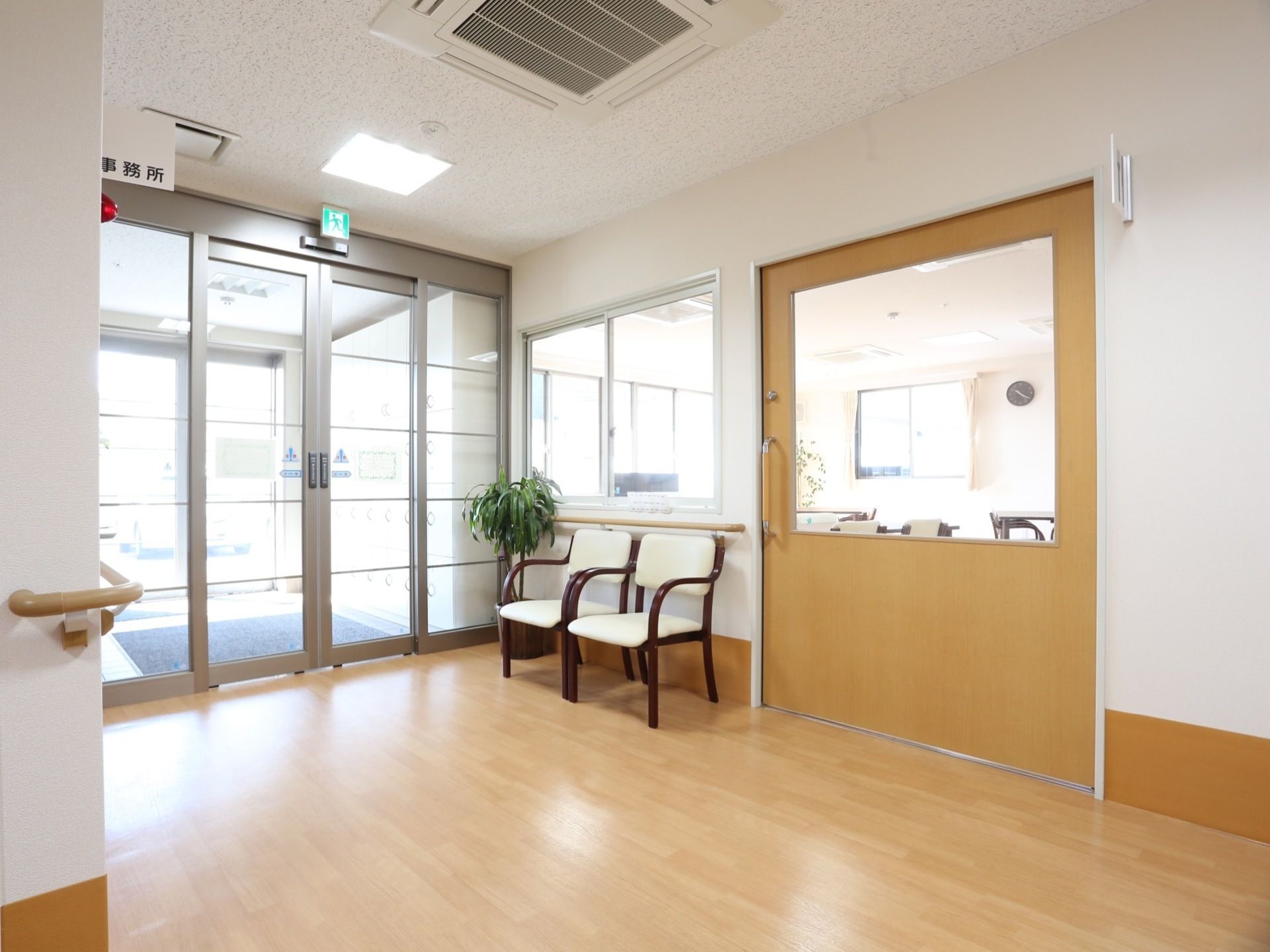 玄関扉は自動扉になっている。玄関ホールに椅子が2脚置かれている。床は滑りにくいフローリングになっている。