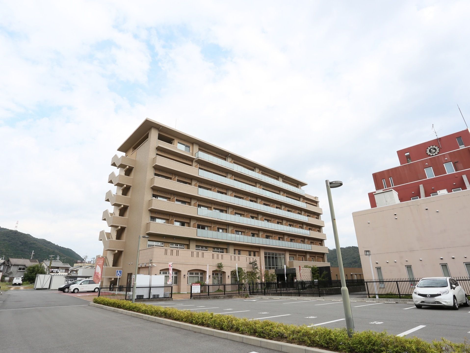 施設の外観がベージュを基調としており、落ち着いた雰囲気である。敷地内に駐車スペースを確保している。周囲に日当たりをさえぎる建物はない。