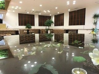 広い部屋の中心に、大きなガラス天板のテーブルがある。天板の下には花や動物の飾り物が透けて見える。床の上には観葉植物がある。