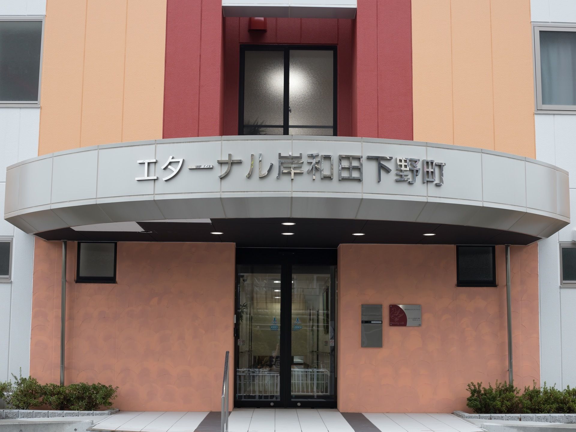 玄関前はスロープになっており、手すりが設置されている。ダウンライトのついた屋根があり、入口は自動ドアになっている。