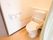 すっきりとした見た目のトイレには、肘掛け付きの便座が設置されている。壁にはスタッフ呼び出し用のボタンが用意されている。