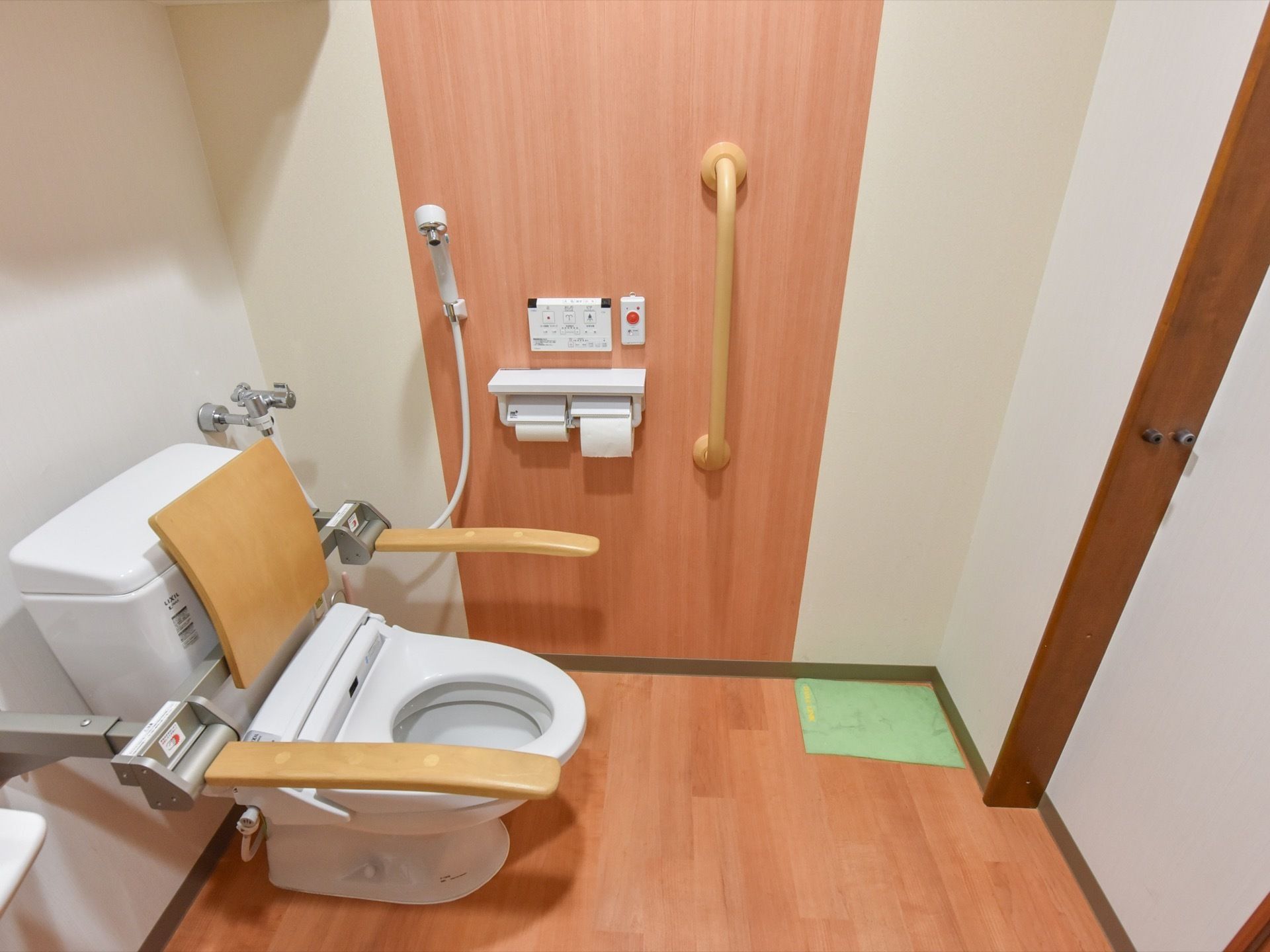 トイレには温水洗浄便座のついた、洋式便器を設置している。壁には手すりがあり、シャワーが取り付けられている。