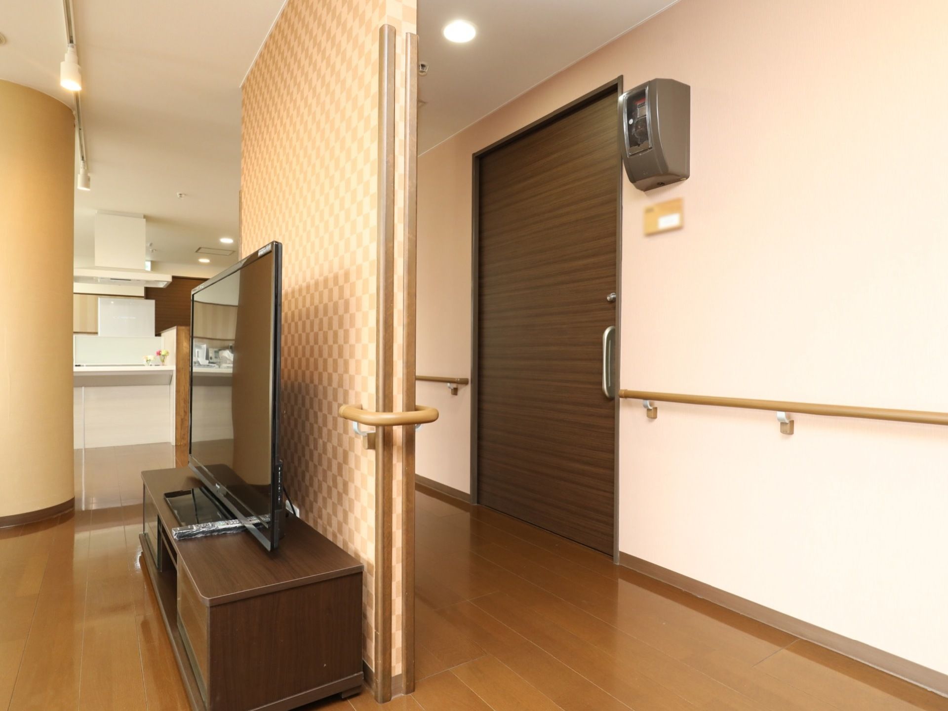 居室のドアがあり、その前に少しスペースを空けて壁がある。壁の内側にはテレビが置かれている。廊下部分の壁には手すりが設置されている。