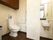 広いトイレ内に、洋式トイレや手洗い場がある。壁には手すりやナースコールが設置されている。大きなゴミ箱がある。