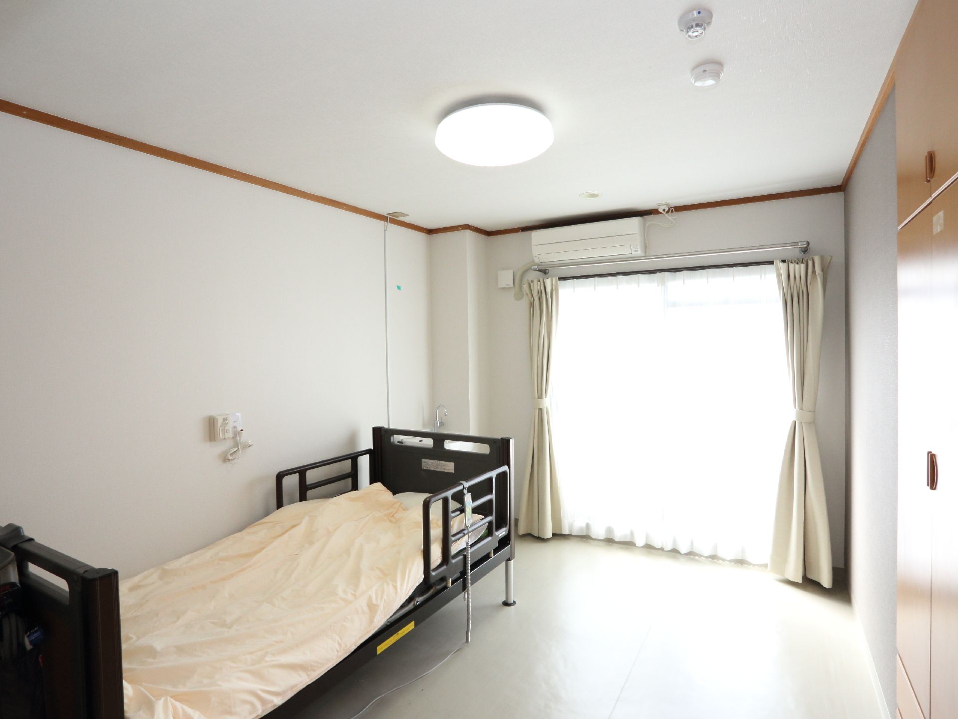 可動式ベッドのすぐ横に、緊急用の呼び出し電話が設置された居室