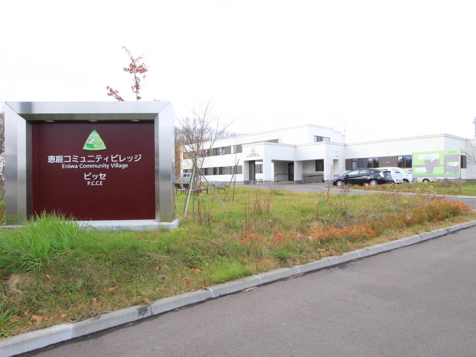 施設入口に、銀色の大きな枠で囲まれた看板が設置されている。ロゴの下に、日本語と英語で施設名称が表示されている。