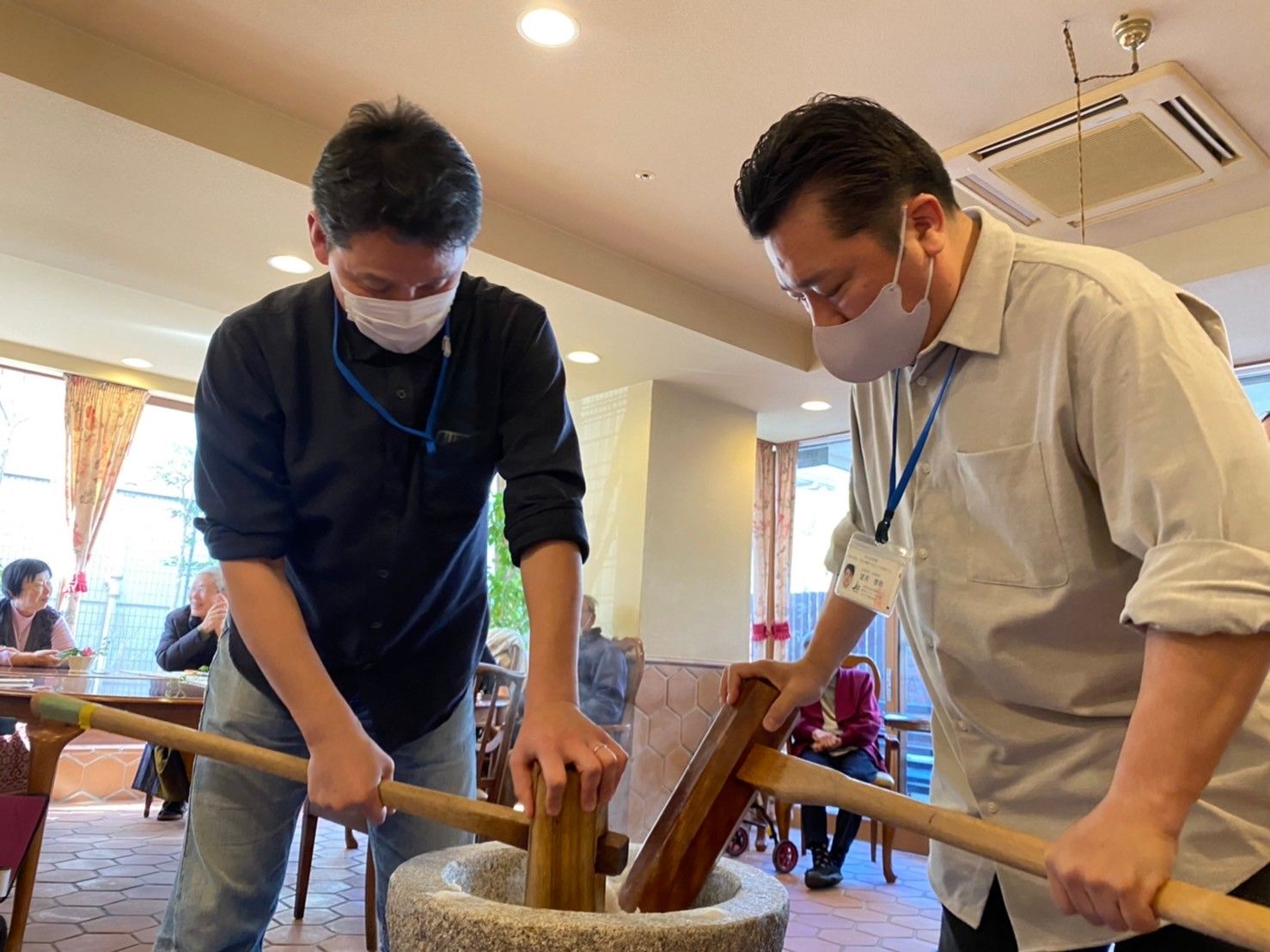 鮮やかな青い空と海が広がる場所で記念撮影をする、満面の笑みの入居者とスタッフ