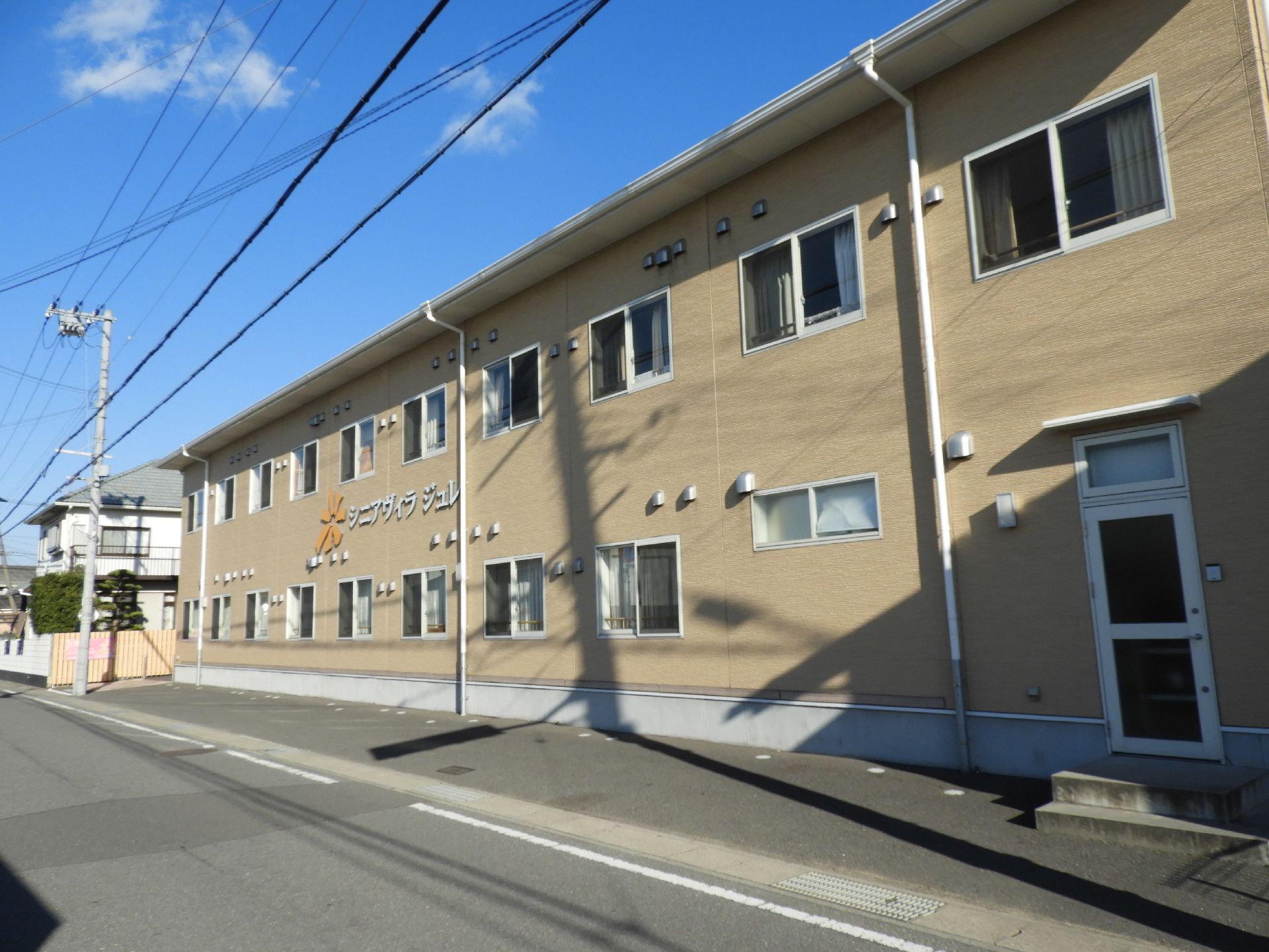 道路沿いに建つ、ベージュ色で統一された2階建ての建物