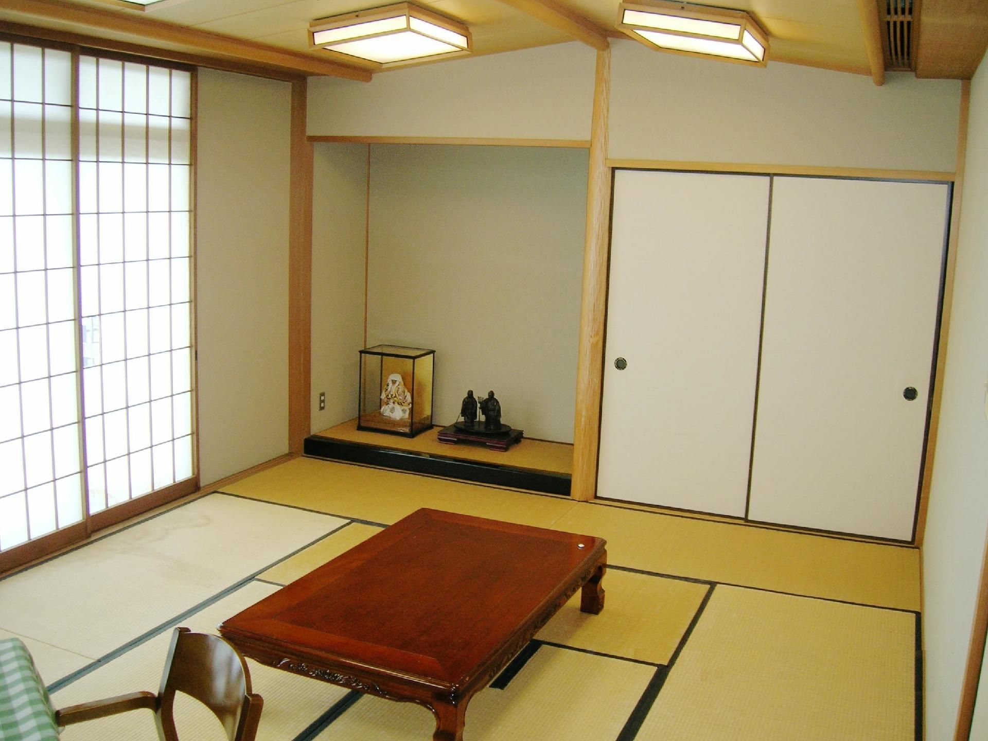 畳が敷かれているタイプの部屋である。中央に木製の机が置かれている。左奥に床の間があり、人形飾りがある。