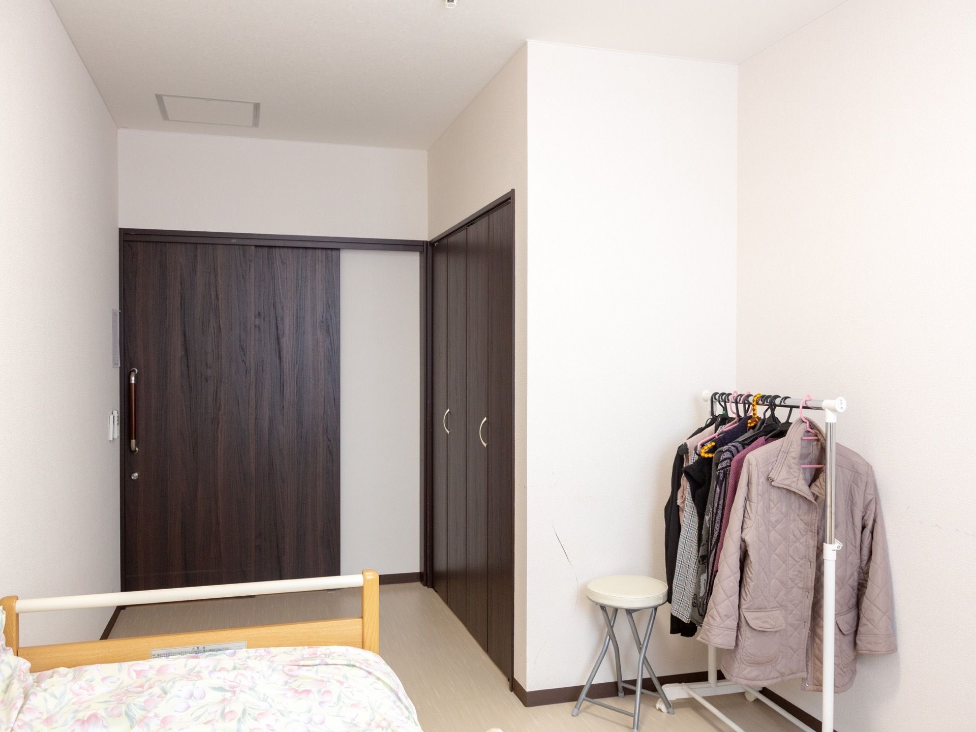 扉は引き戸になっている。ハンガーラックに服がかけられている。収納は大きく、布団や冬服などもしまっておける余裕がある。床は木目調である。