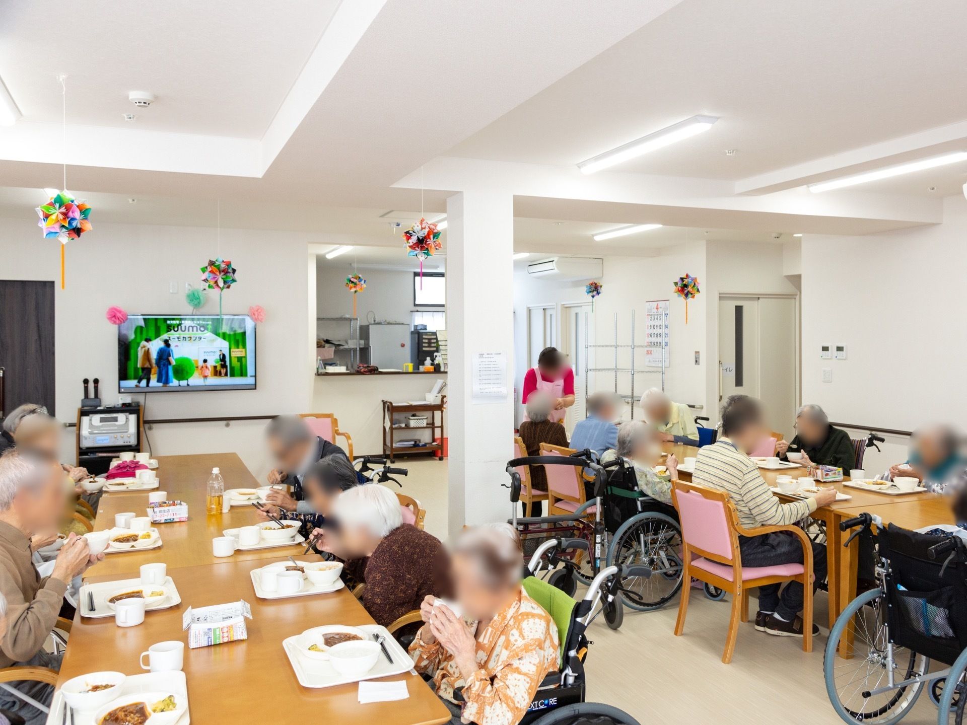 たくさんの入居者様が食堂で食事をしている風景。席から見える位置にキッチンがあり、安心して食事ができる。