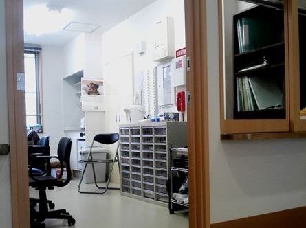 可動式の椅子がいくつか並んでいる。壁にはカレンダーが掛けられており、その奥にはキッチンが設置されている。
