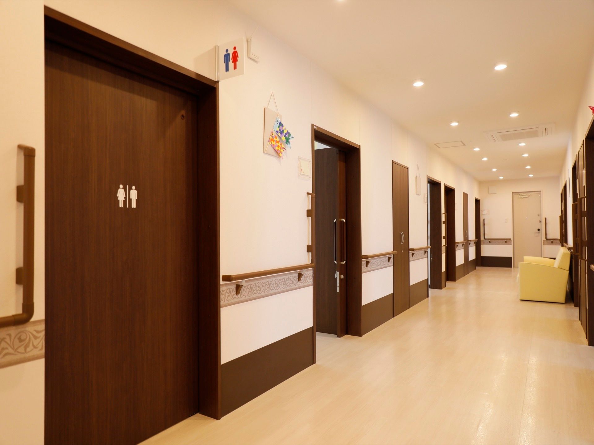 各設備や居室を結ぶ施設内の廊下の様子。トイレなどの共用施設のドアにはピクトグラムの案内が貼り付けられている。