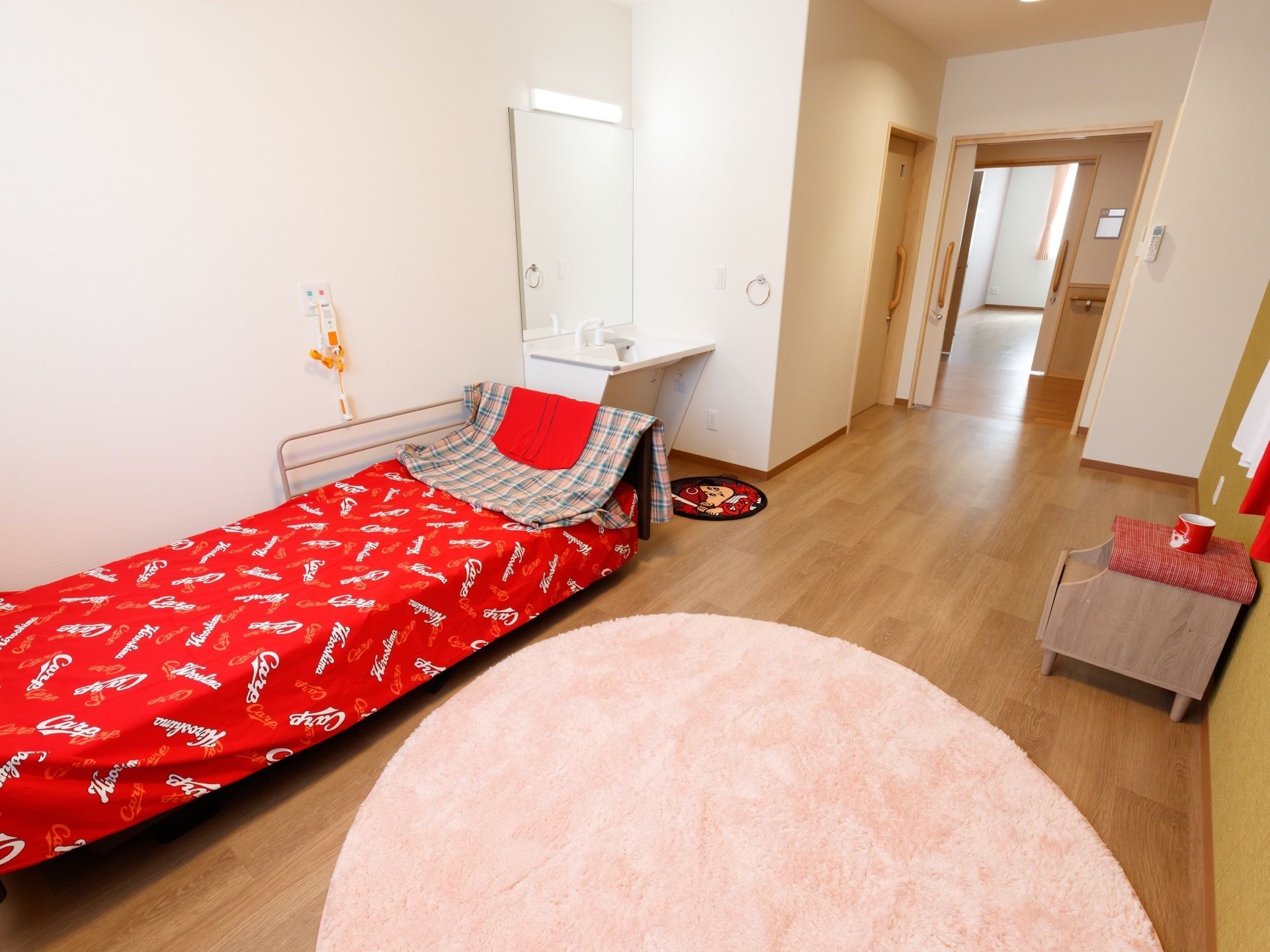 白い壁紙に、フローリングのシンプルな部屋である。ベッドのシーツや、小物が配置されており、生活感がある。