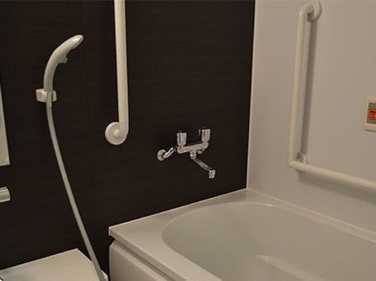 シャワーヘッドの横に手すりが設置された、バリアフリー仕様の浴室