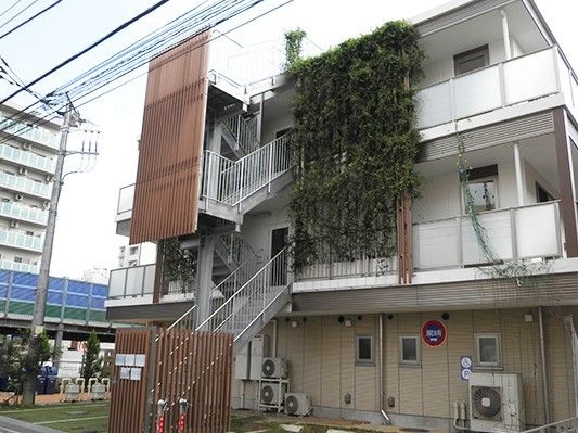 外階段を降りたところに駐車スペースが確保された3階建ての建物