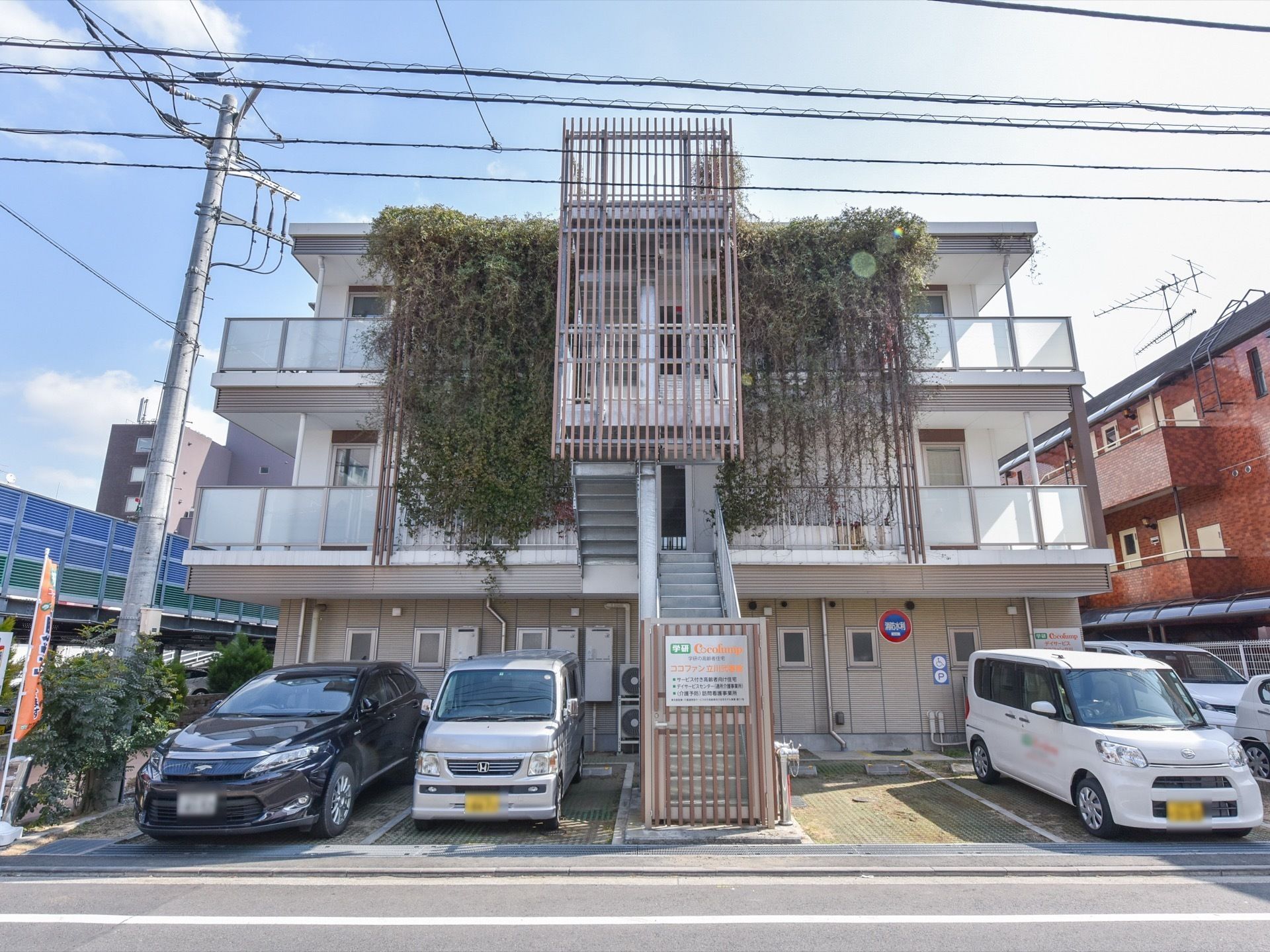 ３階建ての建物である。建物の専用スペースに沢山のつたが絡んでいる緑が印象的である。１階部分に駐車場がある。
