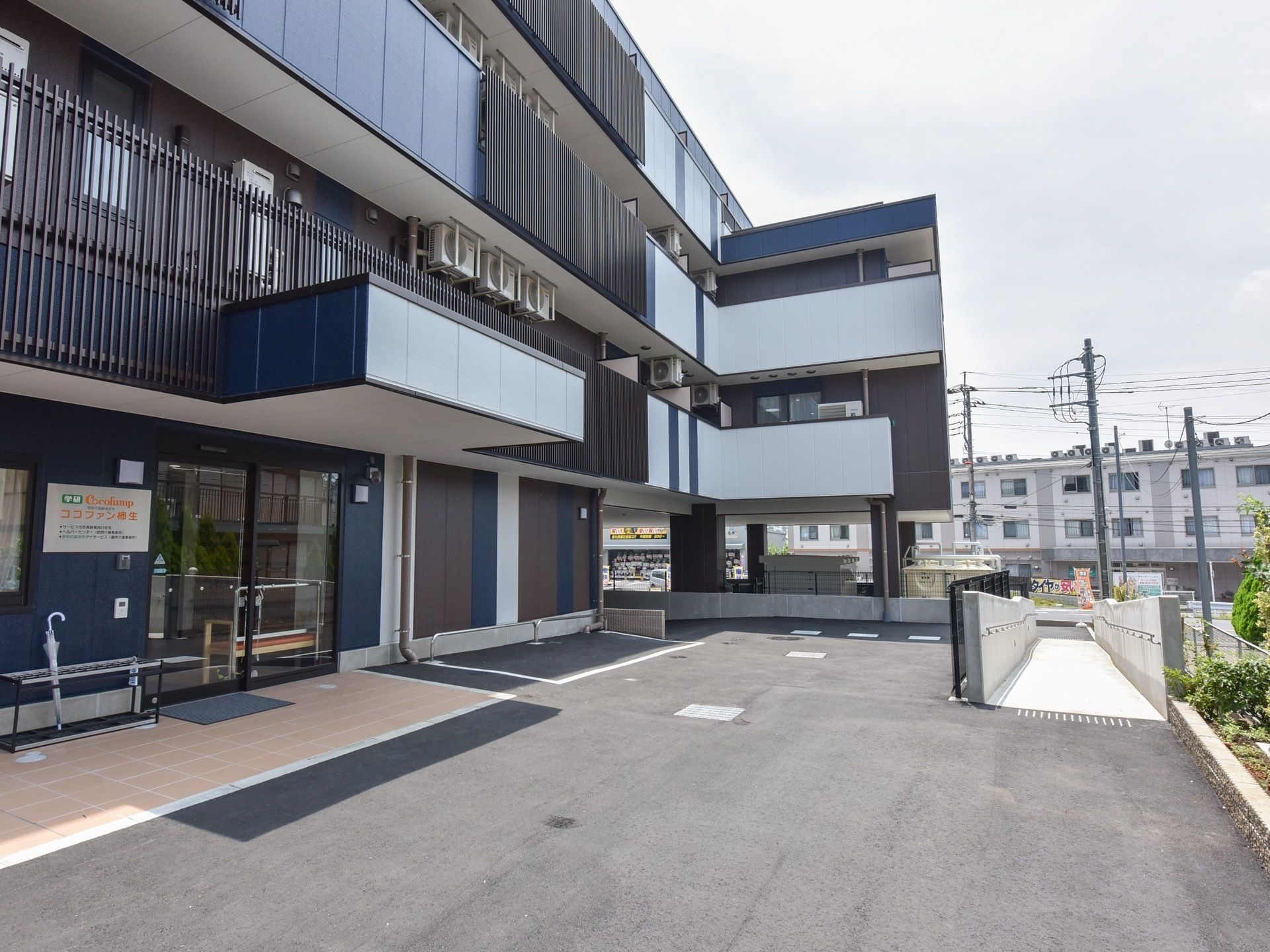 落ち浮いた色合いの建物が写るパース。建物の周りには植物が植えられている