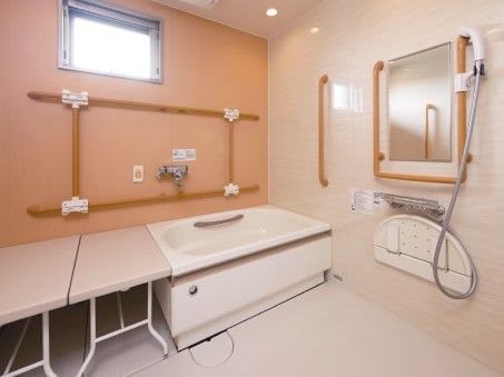 浴室はきれいに磨かれており、入居者様のお身体の状態に合わせた介護設備が整えられている。浴室の壁には、つかまり用の棒が備え付けられている。