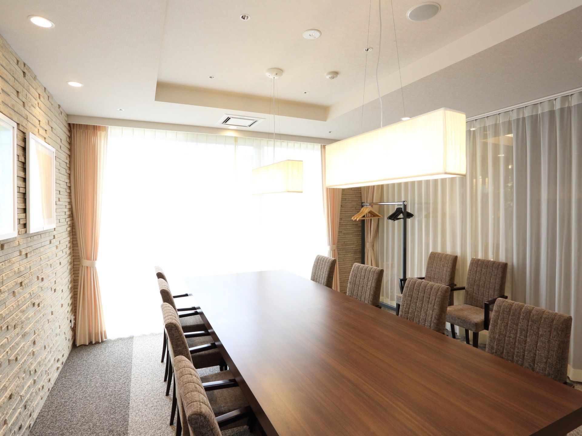 日当たりの良い談話室に大型の木製テーブルを設置している。両側に椅子を配置し、壁際に予備を用意している。