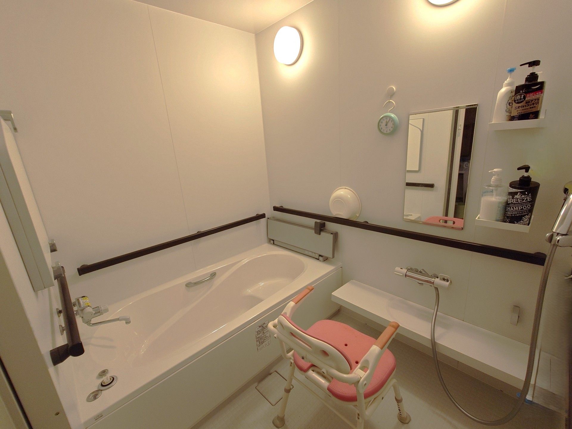 シャワーの下には横幅のある棚が備わっており、桶やシャンプーなどが置かれている。シャワーチェアが用意されている。