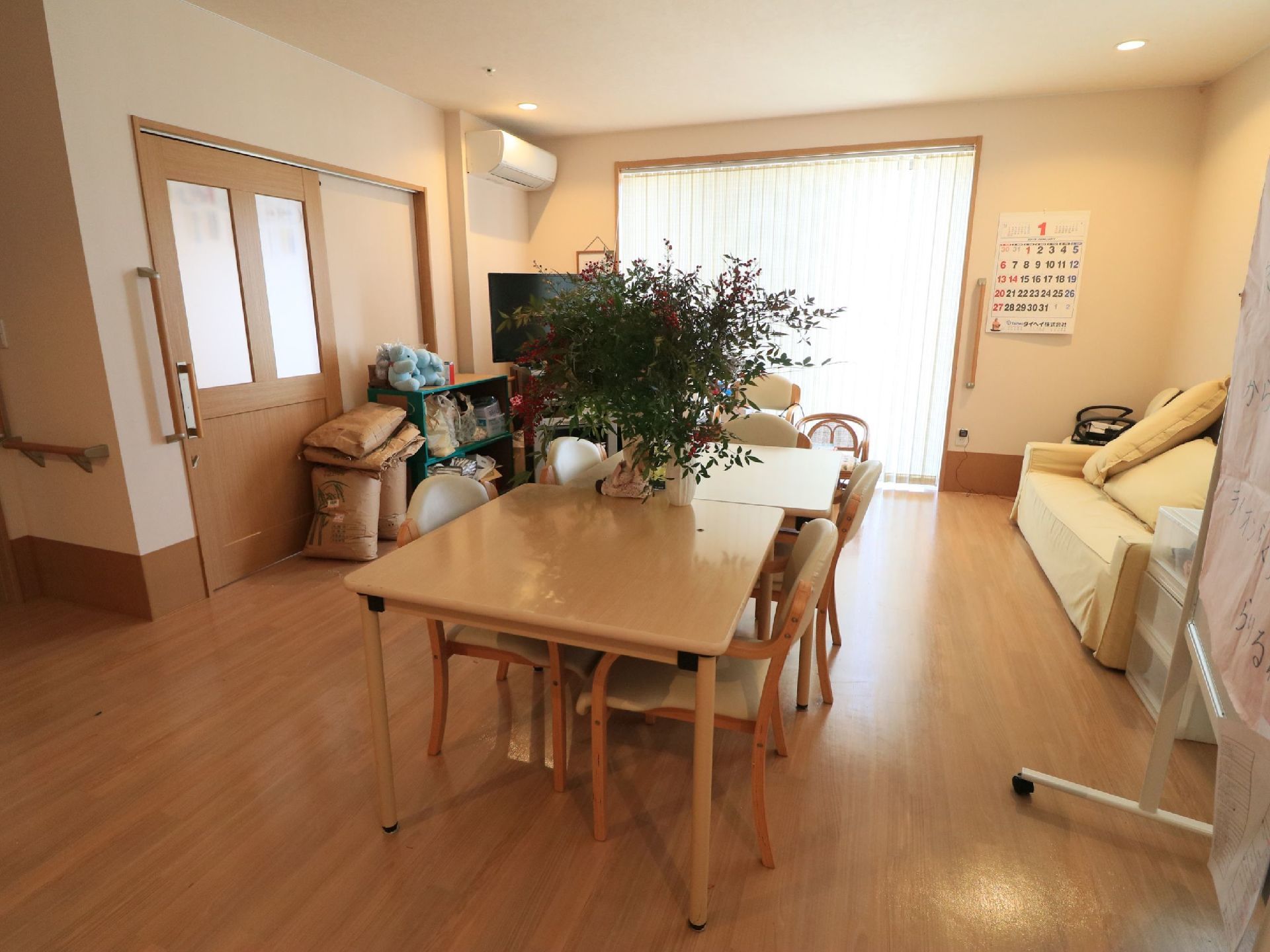 テーブルには花瓶が置かれている。座り心地の良いソファがあり、テレビ鑑賞をお楽しみいただける。壁にカレンダーが掛けられている。