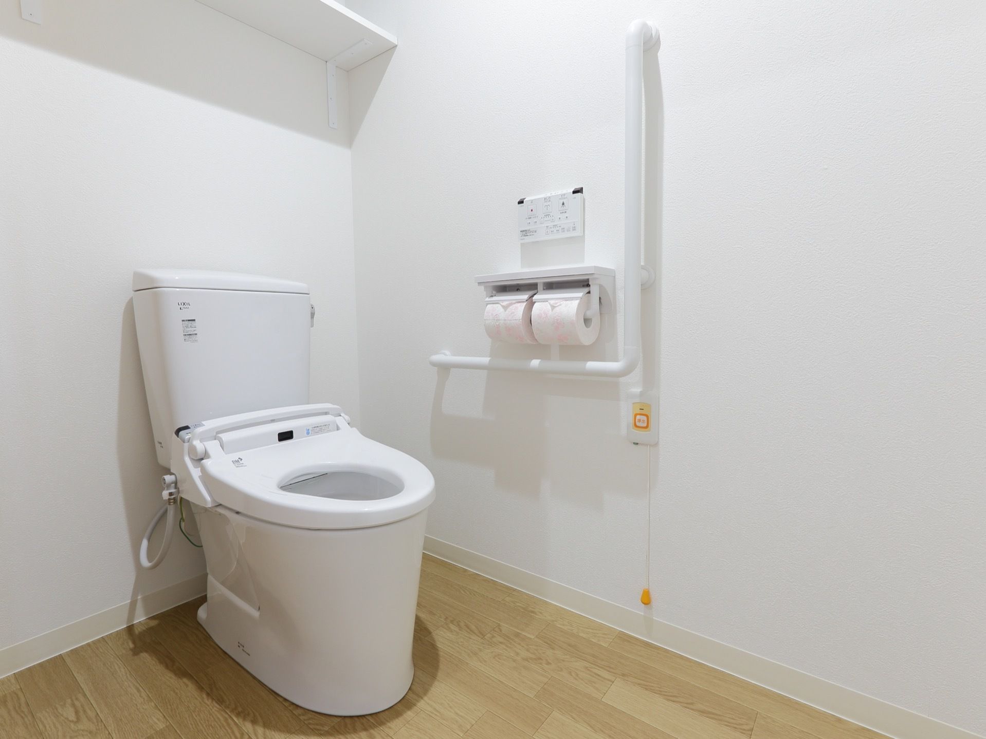清潔感のあるトイレである。壁の上部には棚が設置されており、掃除用具やトイレットペーパーなどを置くことができる。