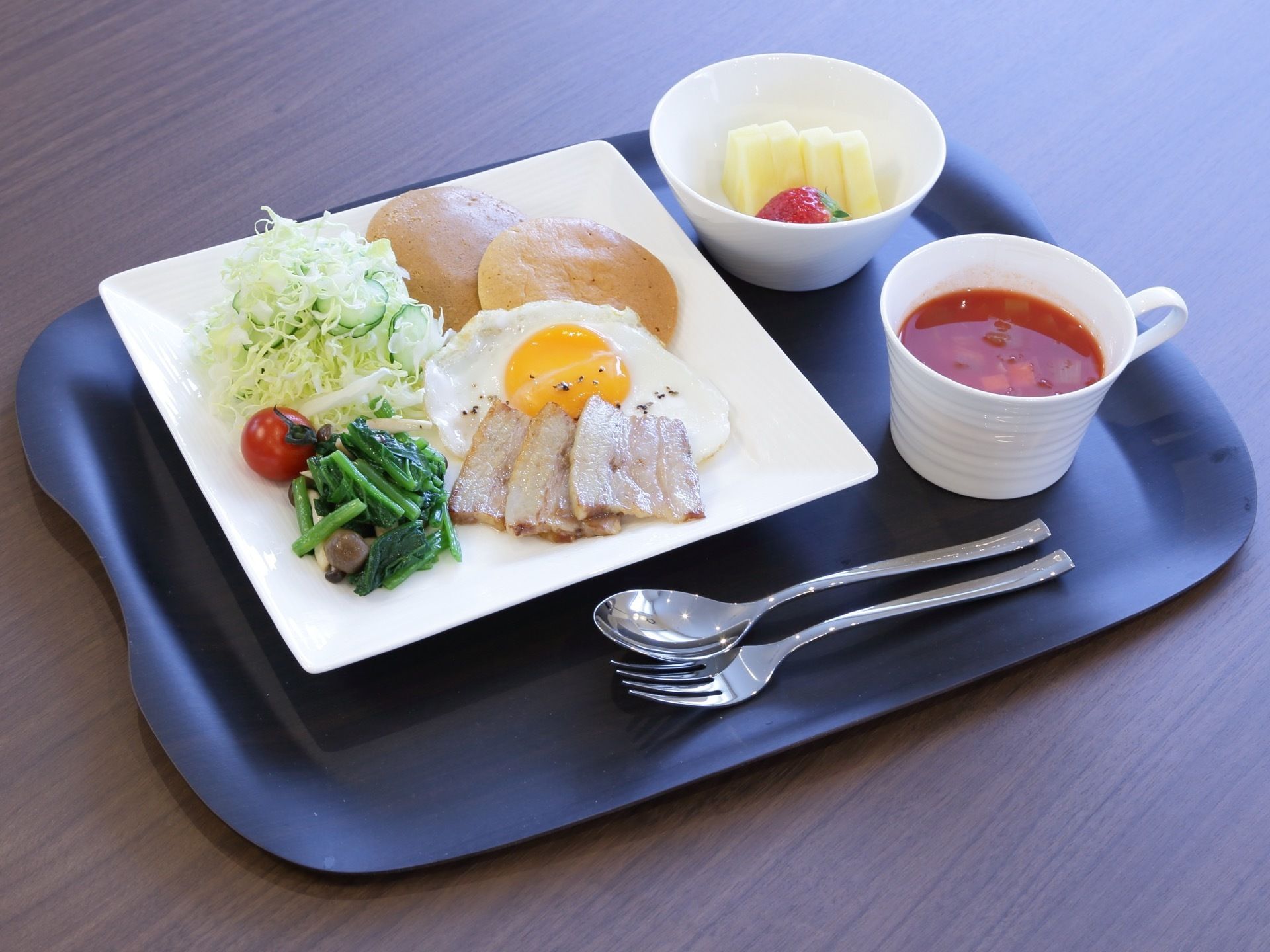 主食にスープと果物が付いた料理である。黒い樹脂製のプレートにそれぞれ白い器を使用し、料理が映えるように工夫されている。
