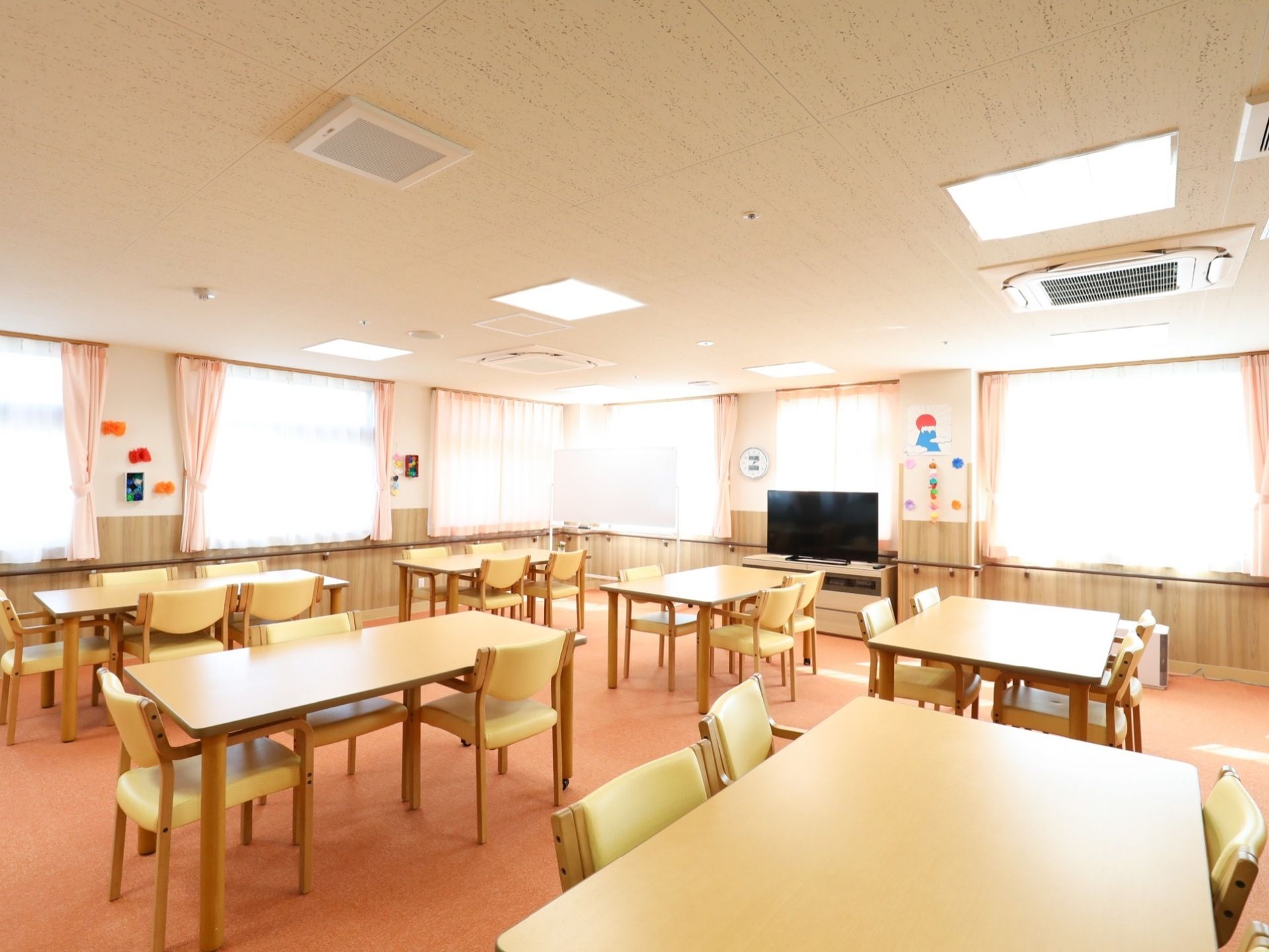 大きな窓がたくさんあるので、日差しがたっぷりと入る明るい食堂である。大きなテレビが置かれていて、壁には手作りの装飾が貼られている。