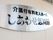 シルバーの丸いステンレスの板に、黒色で大きく施設名が書かれている。表札は玄関の外壁に取り付けられている。
