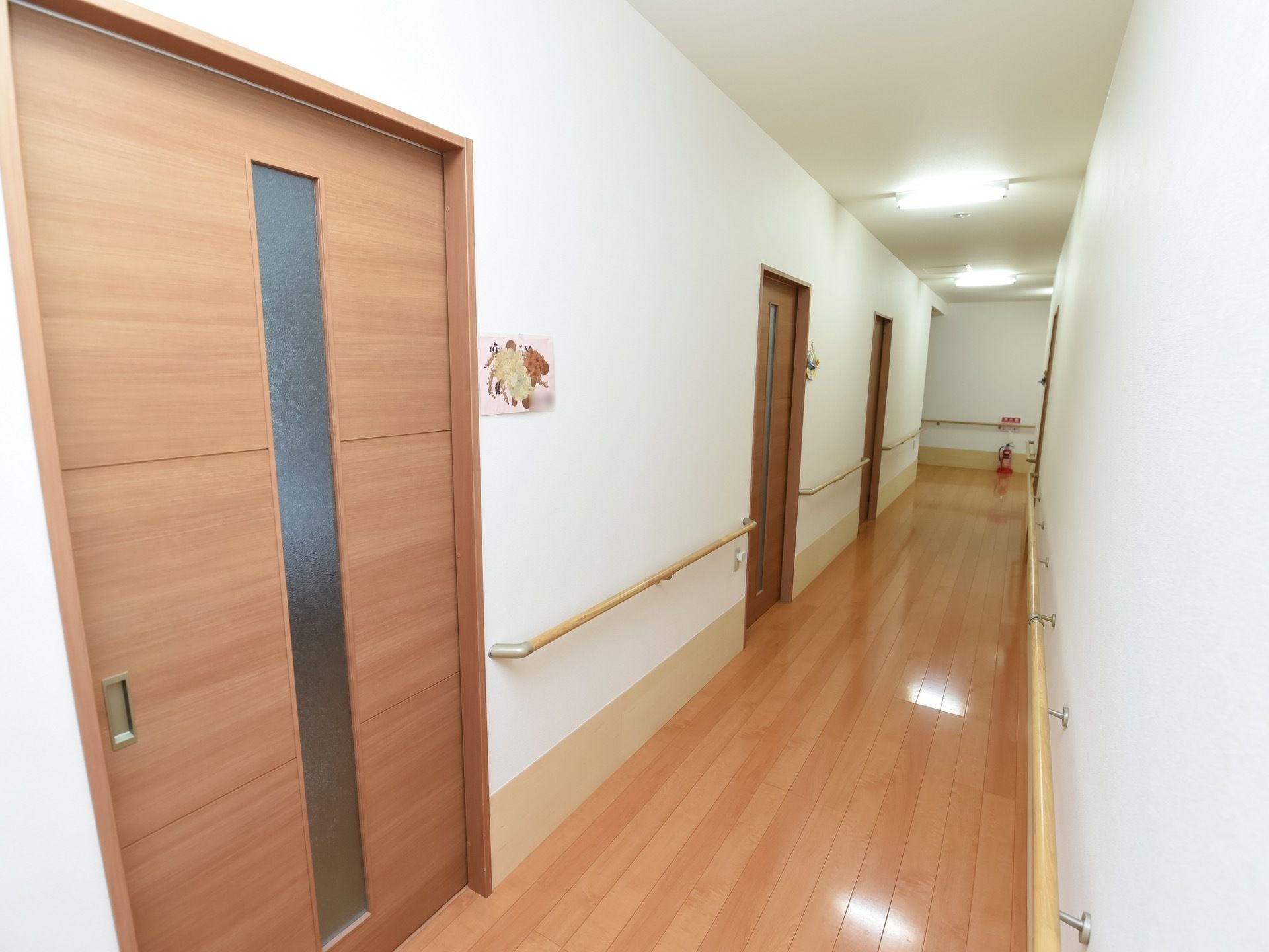 廊下に居室へのドアが並んでいる。扉は引き戸になっており、横にネームプレート代わりのイラストが貼られている。