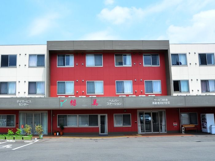 高齢者施設の正面から見た外観。入口前にはベンチと自販機が設置されている。