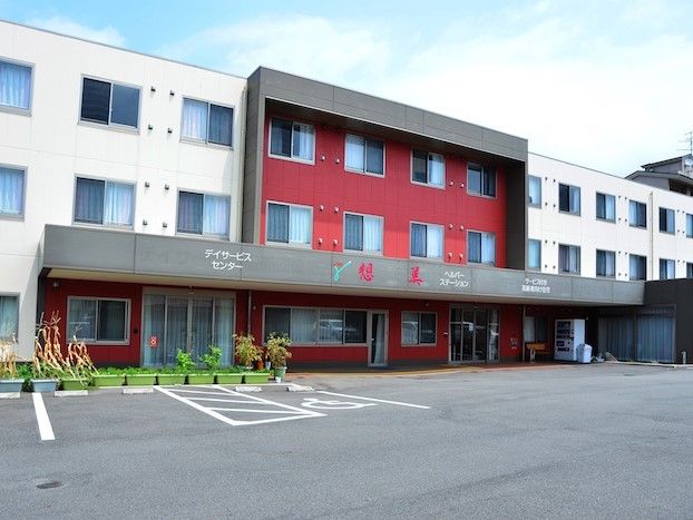 高齢者施設の外観。玄関前に草花を植えたプランターが並んでいる。