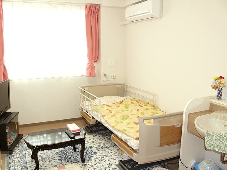 白い壁の居室。窓にはピンク色のカーテンがかかっている