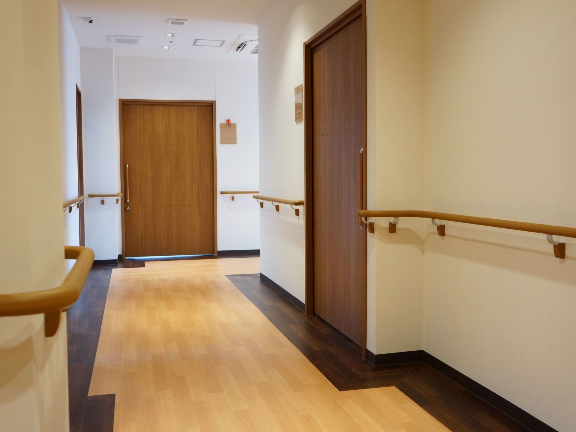 明るく広い廊下である。手すりを壁全面に設置しており、安全に移動することができる。居室の扉はスライド式になっており安全である。