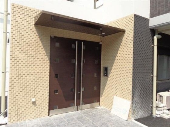 ブラウンの重厚感のある扉が設置され、屋根のついたエントランス