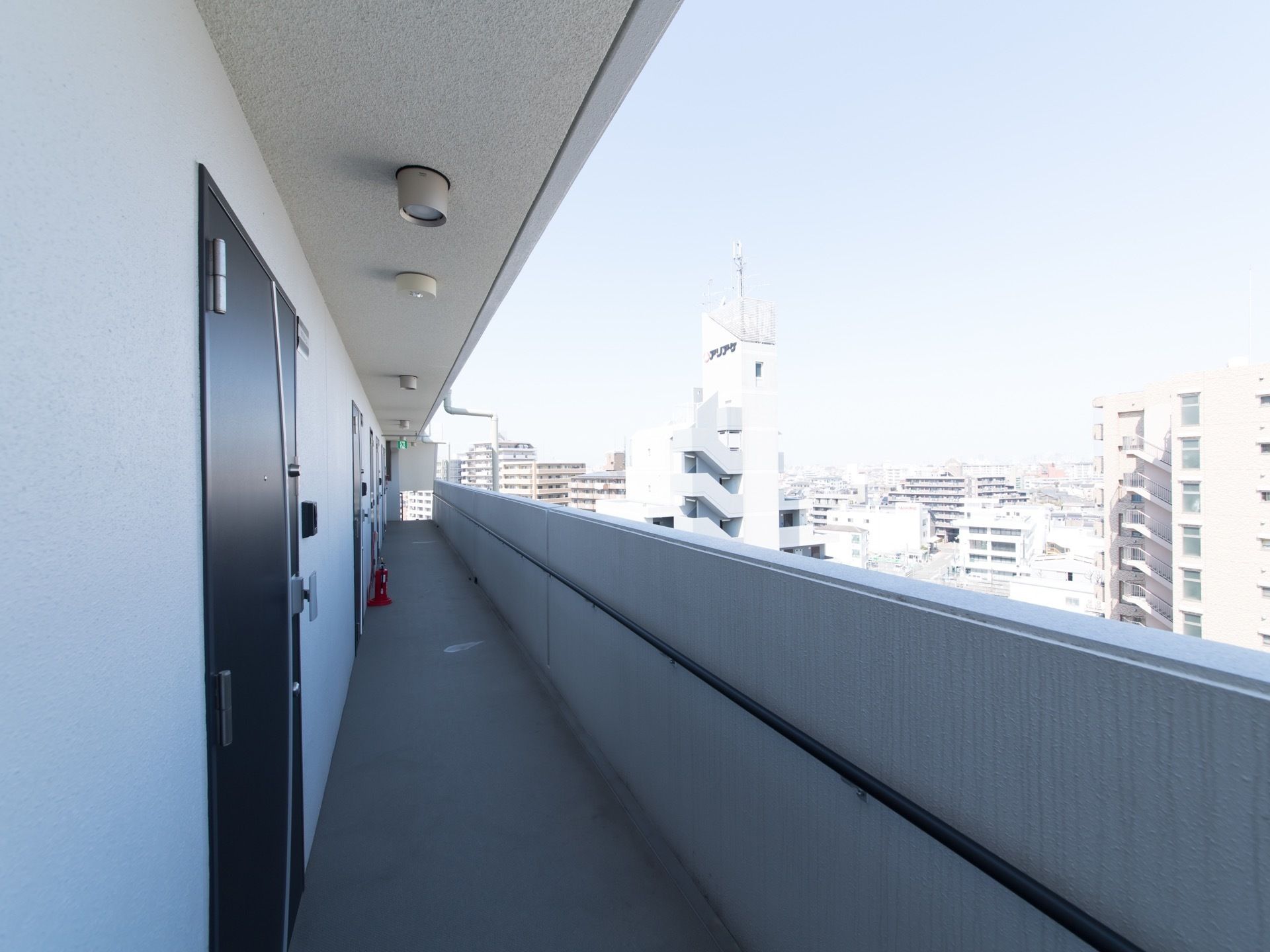 長い通路に各居室へ入る扉がある。通路脇は外の景色を見ることができるコンクリートの壁である。壁には手すりが設置されている。