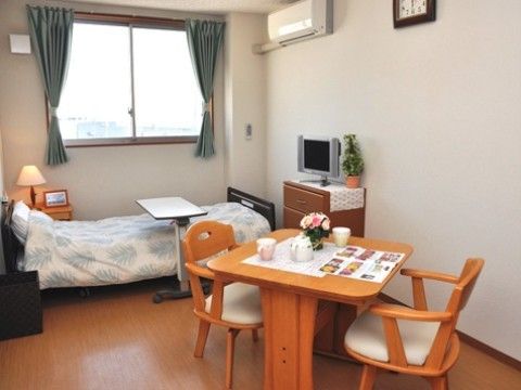 低床型のベッドサイドには腰高窓がある。小さな整理ダンスと、２人用の小さなダイニングセットが置かれている。