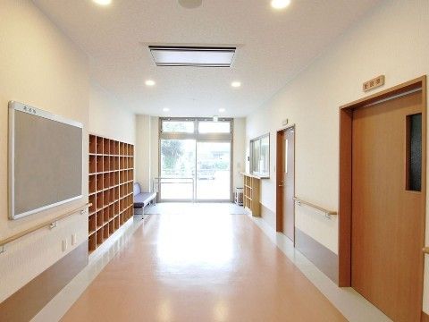 ガラス扉の玄関脇には受付カウンターとソファがある。そこから続く廊下は広々としており、壁には手すりが付いている。