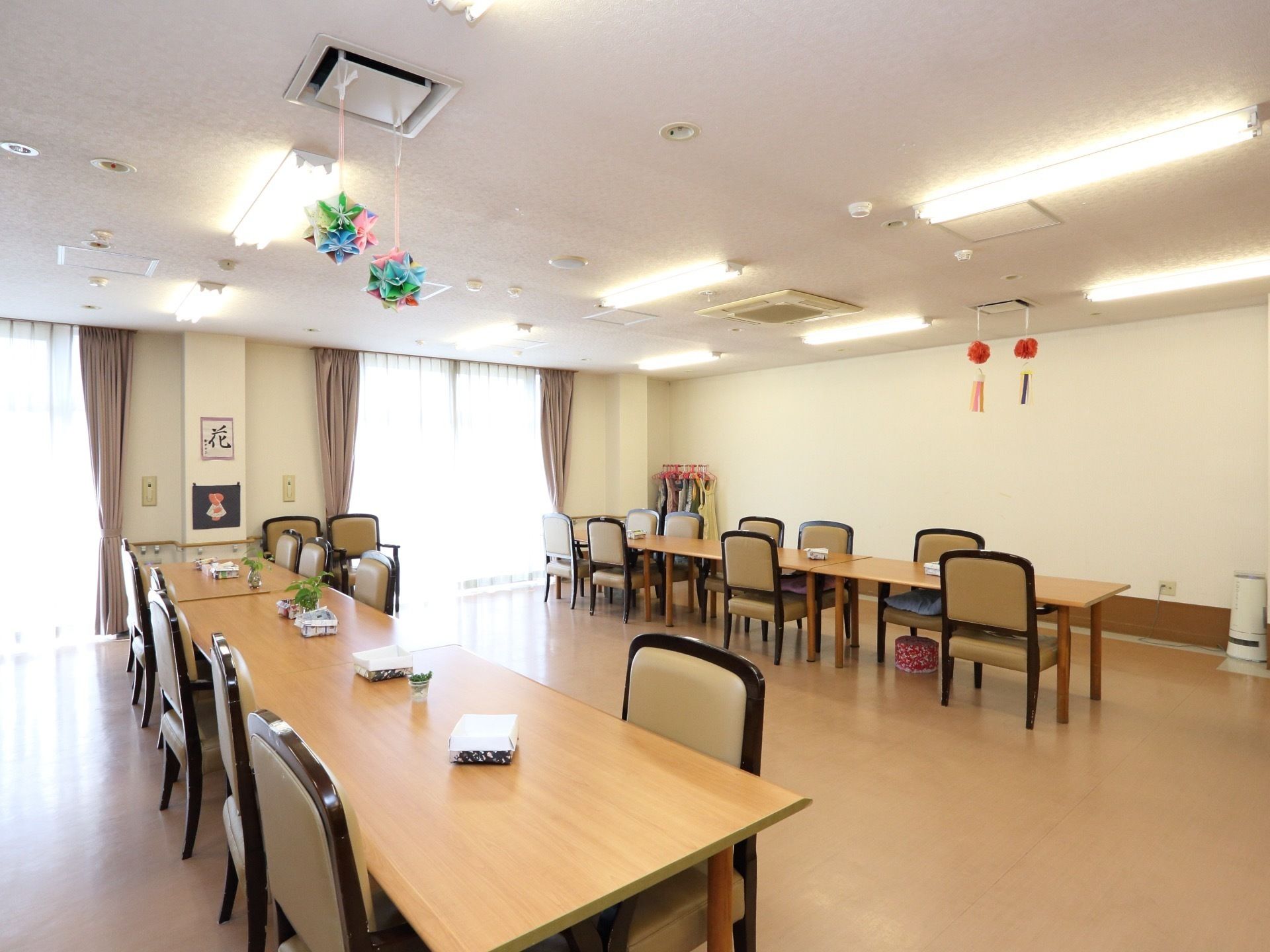 天井から折り紙で作ったくす玉が垂れ下がり、大人数が座れるテーブルが配置された多目的スペース