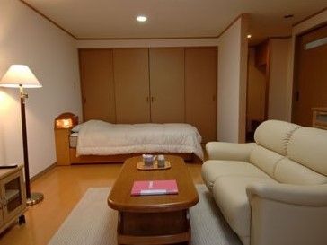 ベージュの色調と間接照明で落ち着いた雰囲気の居室。大きいソファーが準備されているため、くつろぐことができる。
