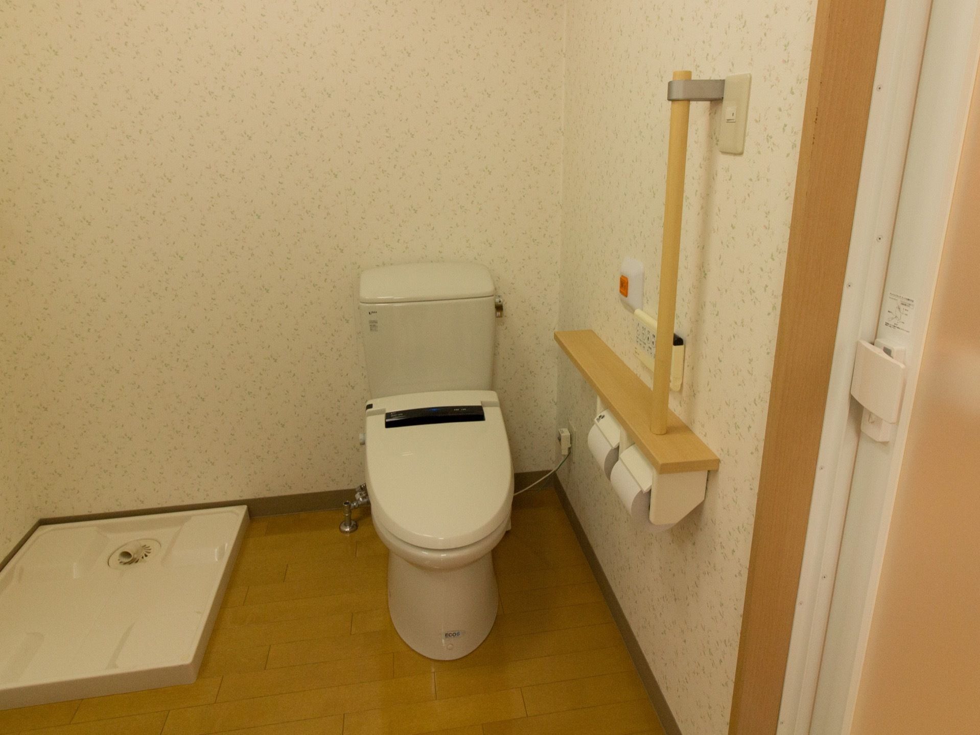 広々としたトイレで、清掃が行き届いている。洋式便座が備えつけられており、となりには洗濯機が置けるトレーがある。