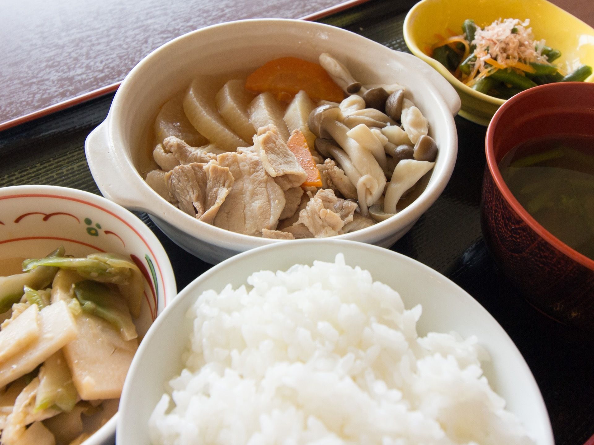 黒色のお盆に色とりどりの食事がならべられている。この日は和風メニュー。根菜類やきのこなど栄養たっぷりである。