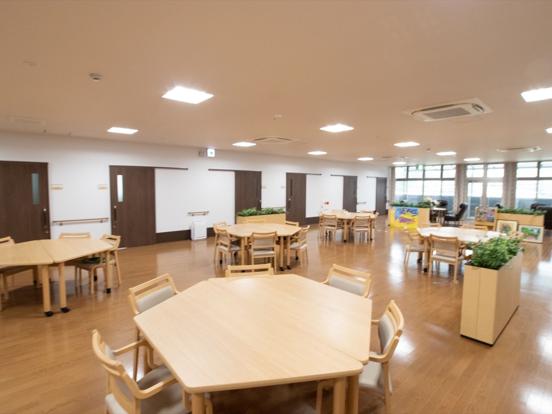 テーブルを２つ組み合わせ６角形型にして設置し、その周りに椅子を置いている。床はフローリングになっている。