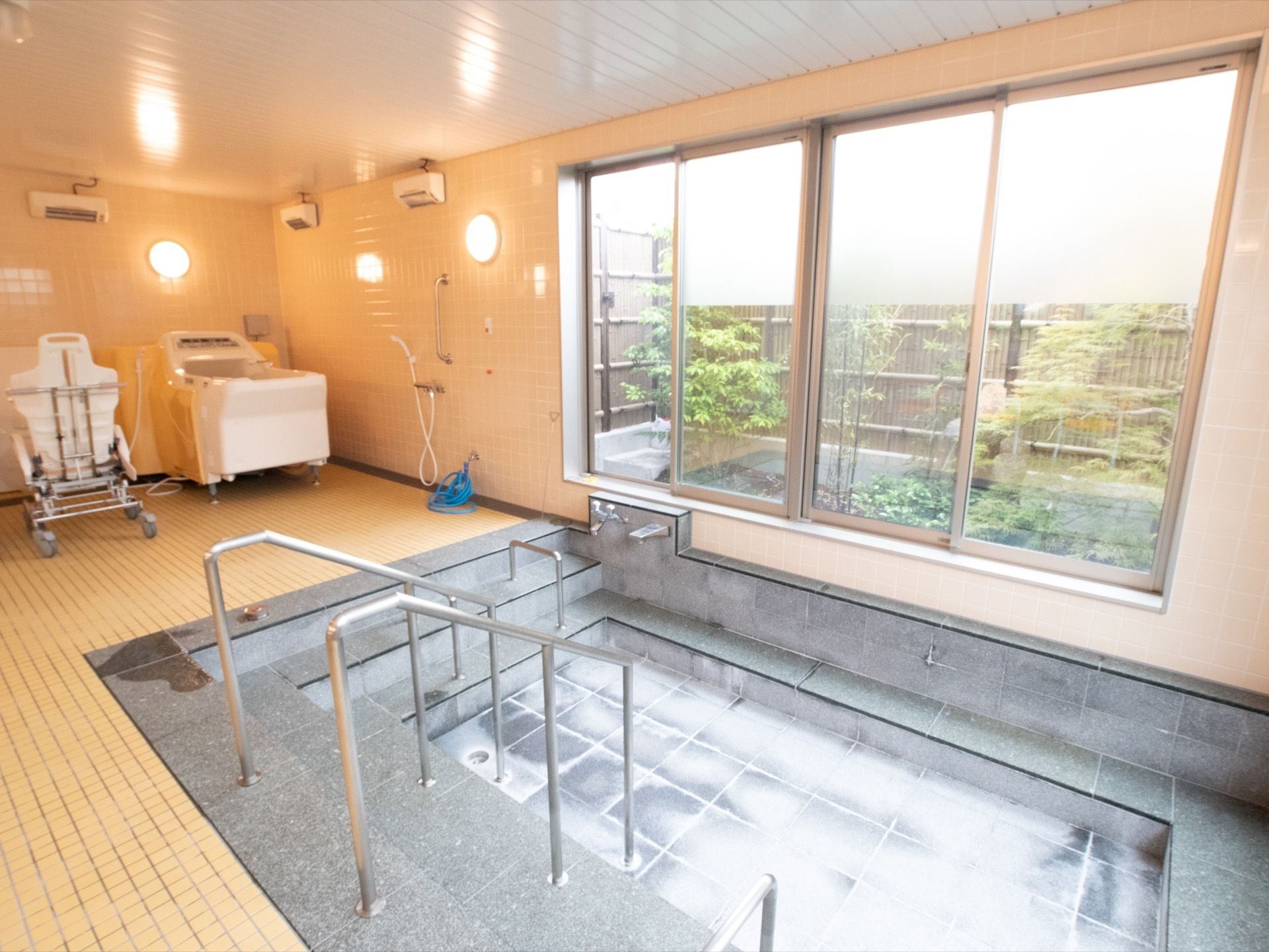 複数の人が入ることができる浴槽がある。奥には機械浴槽が設置されている。大きな窓から景色を楽しむことができる。