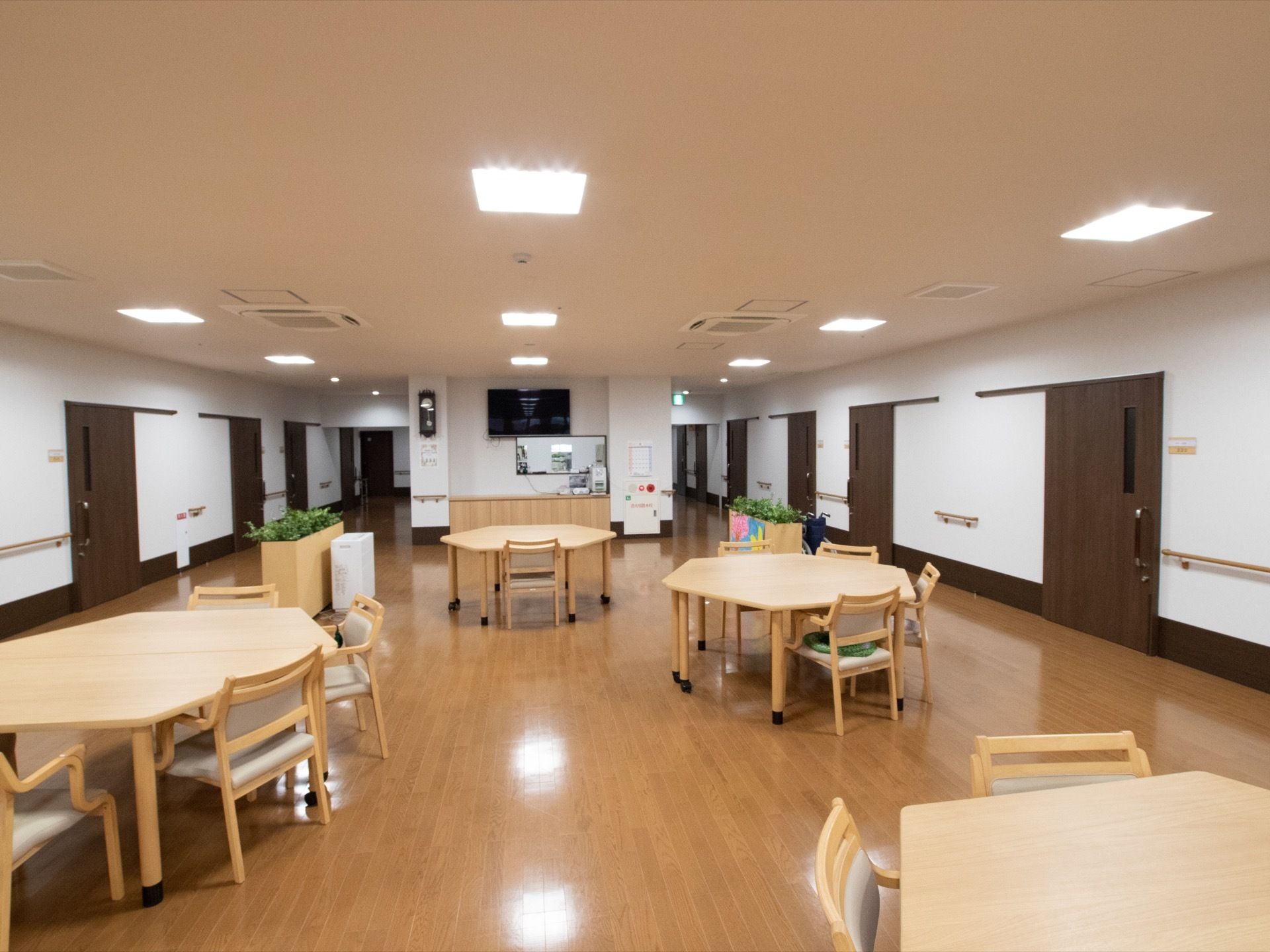 前方の壁にテレビモニターが設置されている。横の柱に時計がある。消化設備のついた火災通報ボタンが用意されている。