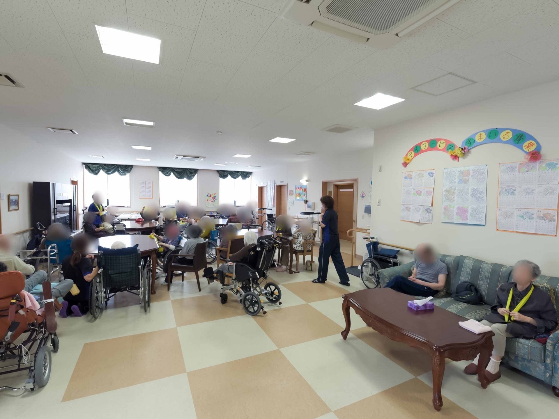 多くの入居者様が集まり、テーブルを囲んで談笑する多目的ルーム