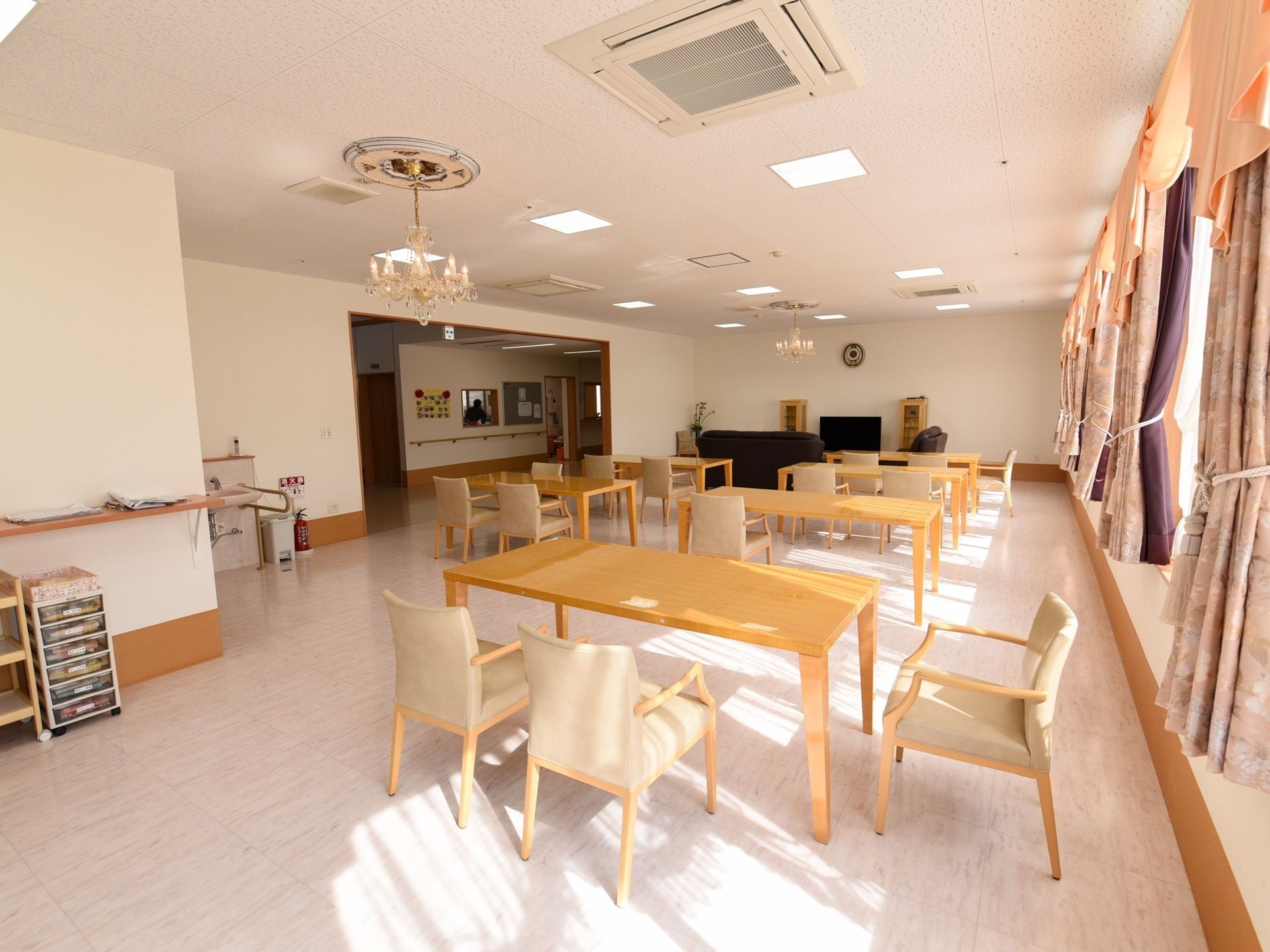 開放的な明るい食堂では、入居者様同士で会話を楽しみながら、食事の時間を過ごせる。天井にはシャンデリアと空調がある。